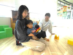 ママのおひざに座る誕生児の男の子とそれを見守るパパの様子