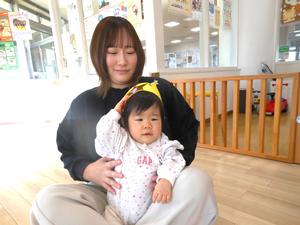 ママのおひざに座り冠を外そうとしている誕生児の様子