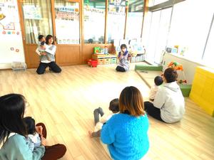 保育士による読み聞かせを見ている親子の様子