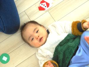 ゴロンと床に寝転がってカメラ目線の男の子の写真