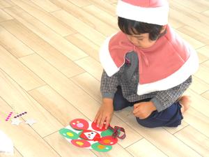 集中してシールを貼る、クリスマスの衣装を着た女の子の様子