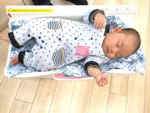 体重測定器に乗って眠っている赤ちゃんの様子
