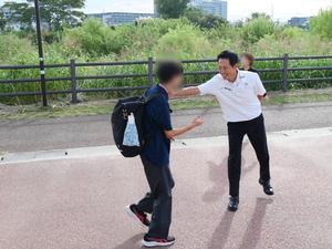 校門で登校生徒に笑顔で挨拶をする市長