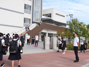 校門で登校生徒に笑顔で挨拶をする市長