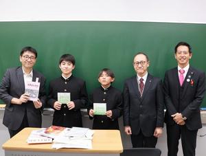 黒板の前で田中先生、中学生、教育長、市長とで記念撮影