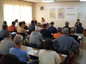 マイクを持って説明する政策室長