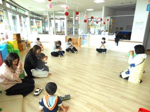 保育士の真似をして手遊びをしている親子達の様子