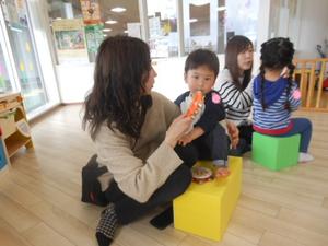 カラー積み木に座って鈴を見ている男の子の様子