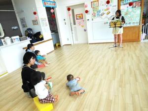 ウクレレ演奏をしている保育士とそれを見ている親子の様子