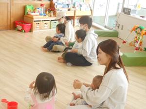 保育士の手遊びを見ている3組の親子の様子