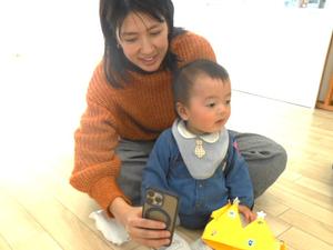 冠を取る誕生児の男の子とその様子をスマホで撮るママの様子