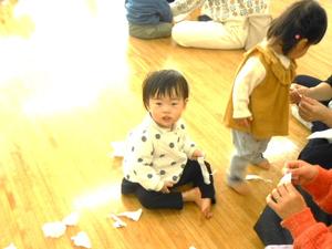 紙をちぎりながらカメラに目を向ける女の子の様子