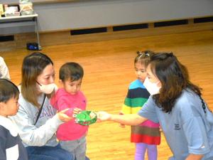講師の先生が持つかえるのタンバリンを叩く親子の様子