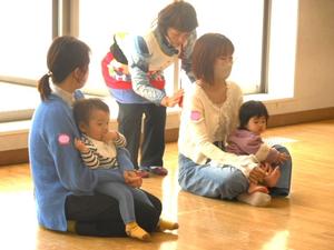 講師の先生のタッチケアを受けるママとママの膝に座る女の子の様子