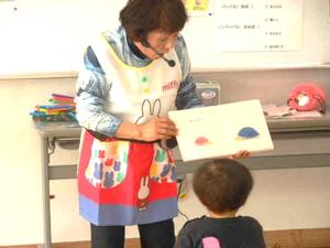 講師の先生の絵本の読み聞かせを近づいて見ている男の子の様子