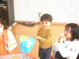 嬉しそうにボールを網ですくう男の子と見守るママの様子