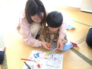 工作ではさみで紙を切っている親子の様子