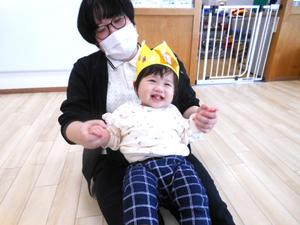 笑顔の誕生児の女の子を膝に乗せているママの様子