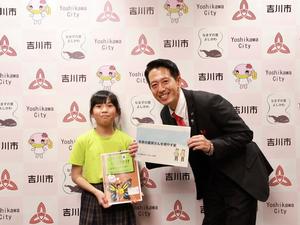 花本さんの論文と提言書を持って市長と記念撮影