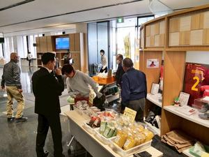 市役所入り口の地場産野菜や市特産品を販売するブースを確認する市長