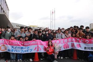 横断幕と多くの市民をバックに笑顔で撮影に応じる小野光希選手