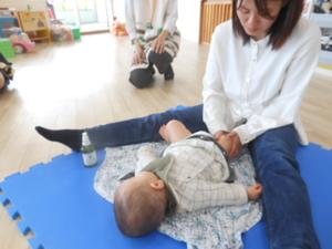 一人の赤ちゃんが母親に太ももを優しくオイルマッサージしてもらっているところ