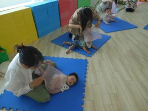 別の親子が同じく柔らかい布を使って感触遊びを楽しんでいるところ
