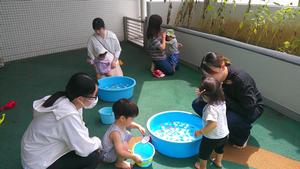 テラスで水を張ったたらいで遊ぶ複数の親子