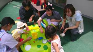 テラスで水を張ったビニールプールで遊ぶ親子連れ