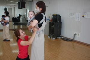 講師の先生に抱っこひもの正しい付け方を指導してもらっている様子