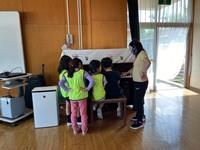 子どもがピアノを弾いているのを大人が見守る様子