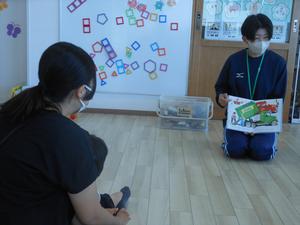 大学生のお姉さんが車の絵本を読んでくれている写真