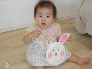 うさぎのポーチを下げているカメラ目線の赤ちゃんの写真