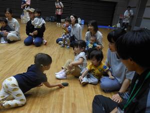 ゴーヤ型のマラカスをお友だちに貸そうとしている女の子の写真