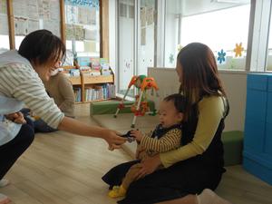 バイキンマンのお人形を持った先生が赤ちゃんにご挨拶している様子
