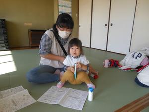 双眼鏡作りで嬉しそうにクレヨンを持つ女の子の写真