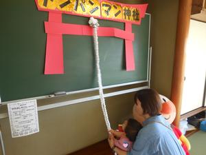アンパンマン神社で鈴を鳴らしてお参りする親子の写真