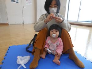 うさぎ風船を作っているママと手作りおにぎりを持ってカメラを見る赤ちゃんの写真
