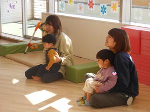 ママのお膝で、読み聞かせを見ている二組の親子