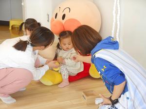 大きなアンパンマンに座って、お年玉をもらう女の子の写真