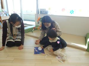 画用紙に丸形を貼りつけている女の子とママの様子