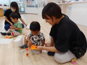 工作でママとシール貼りをする男の子の写真